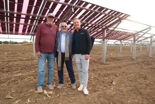 Three people standing beneath elevated solar panels at the agrivoltaics research site.